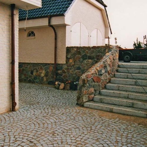 Kleinpflaster aus Granit kombiniert mit einer Natursteinmauer